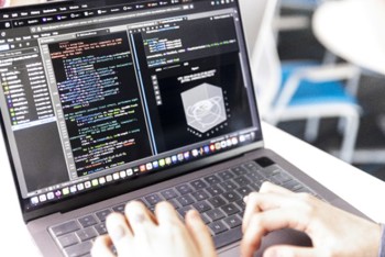 a person typing computer algorithms on a laptop